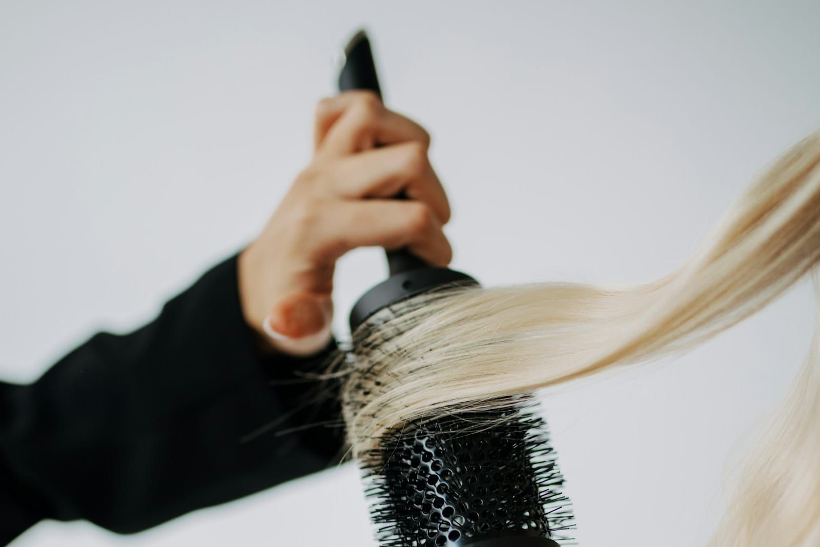 Frizerski salon u Kragujevcu, ilustracija: frizerka okruglom četkom oblikuje pramen duge plave kose